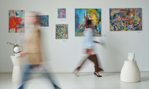 Visitors Walking Past Abstract Art in a Gallery