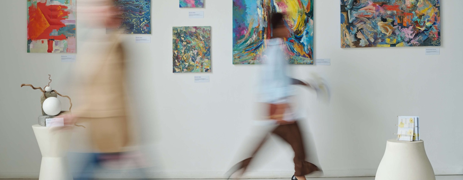 Visitors Walking Past Abstract Art in a Gallery
